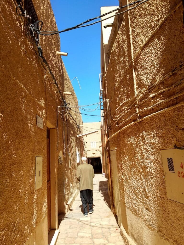 The Labyrinths of the M'zab Valley: In Search of the Cyclopes of Ghardaïa 5 A M'zab Berber man in Ghardaïa wearing traditional Mozabite dress — a navy-blue sirwal (wide-topped, calf-tight pleated trousers) and a white chéchia cap traditional Ibadi Berber costume of Algeria's M'zab Valley.