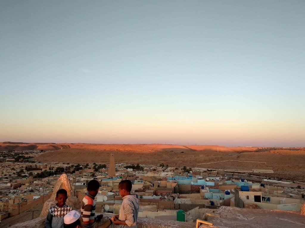 The Labyrinths of the M'zab Valley: In Search of the Cyclopes of Ghardaïa 9 Aerial skyline view over Ghardaïa, showing the tiered ochre houses of the M'zab ksar climbing the hillside toward the pyramidal Ibadi minaret at its summit — the Mozabite Berber pentapolis in Algeria's Saharan M'zab Valley.